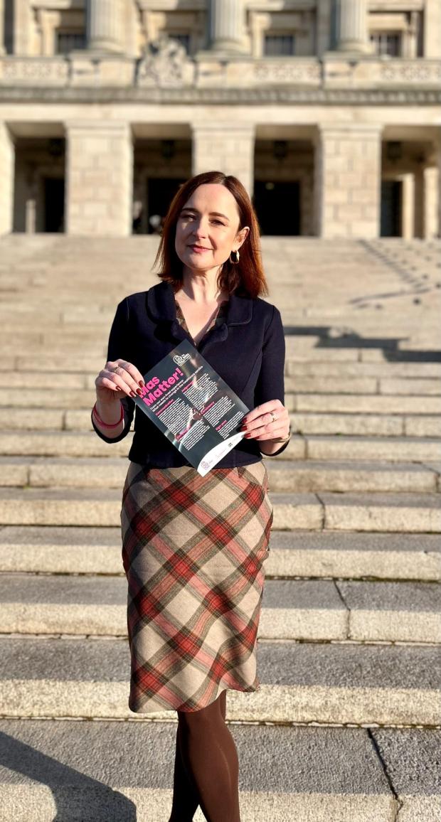Profess Siobhan O'Neill in front of Stormont holding the newly launched Mas Project Leaflet